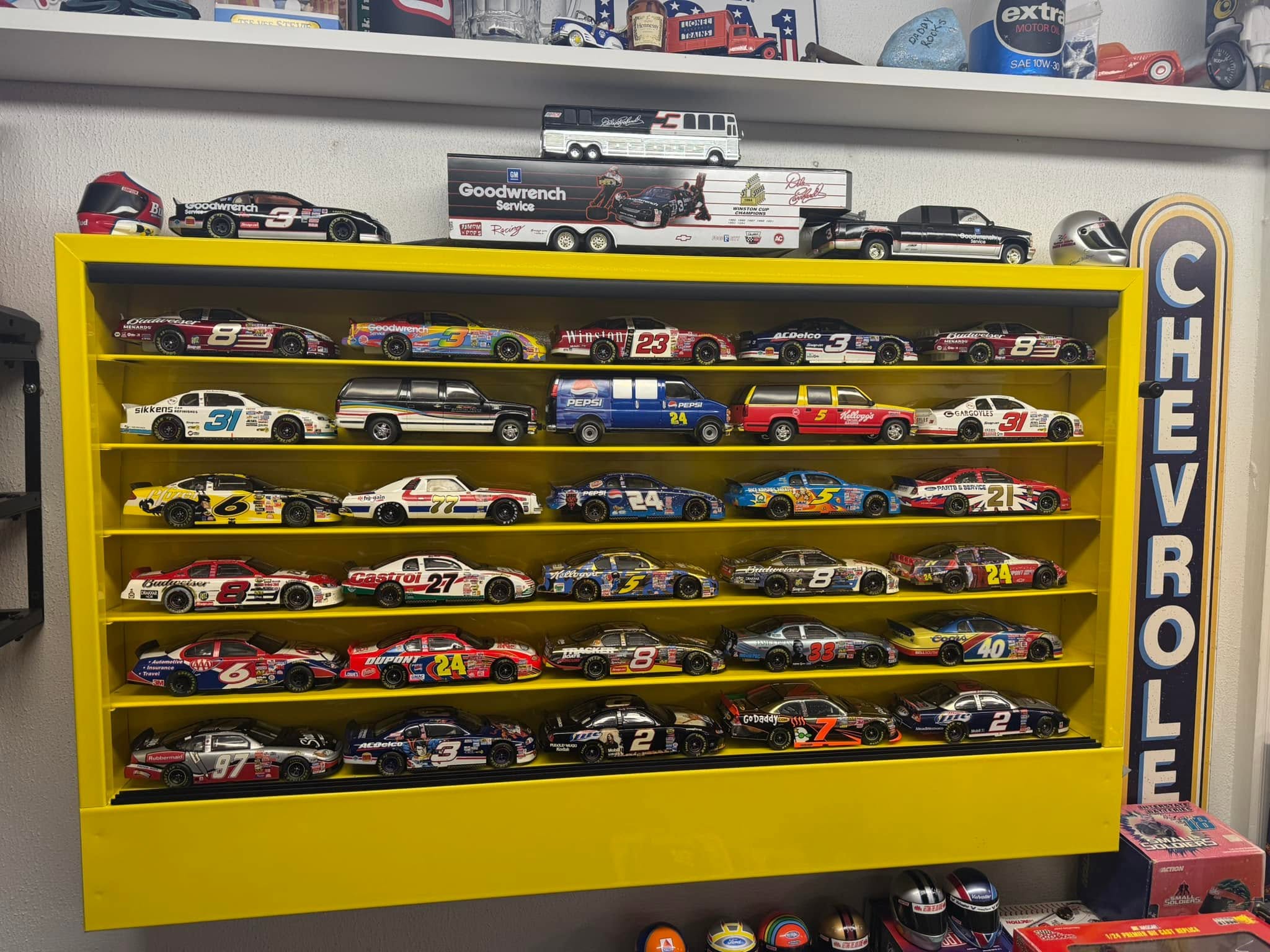 A yellow display cabinet filled with NASCAR diecast cars and racing collectibles